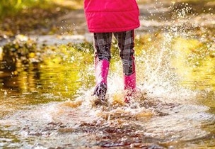 Child in pink gum boots jumping in a puddle