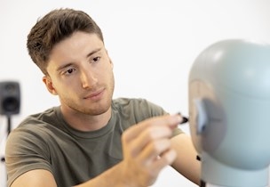 Man working on hearing solution on mannequin
