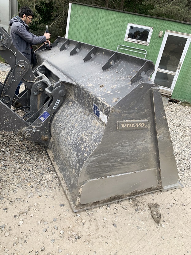 Prototype being mounted for feasibility testing on a wheel loader bucket in a gravel pit.